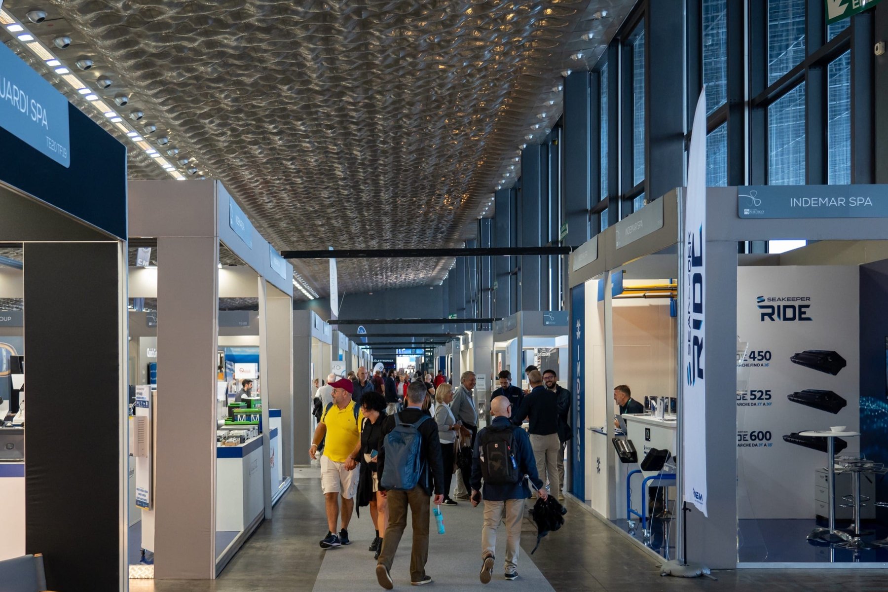 Pasillo del área TechTrade del Salone Nautico di Genova, con stands de fabricantes de equipos y visitantes profesionales